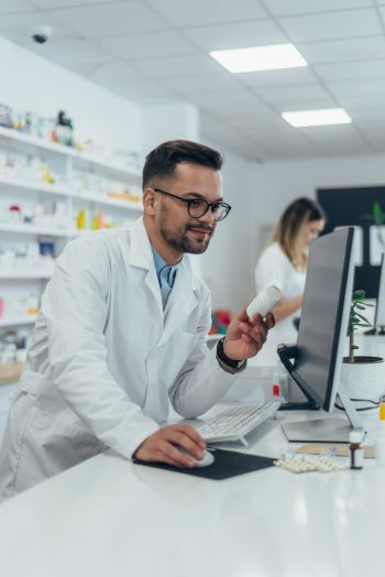 Portrait of a handsome pharmacist working in a pharmacy and using a computer