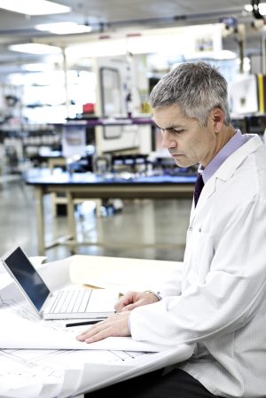 A male caucasian technician in white coat using a laptop computer